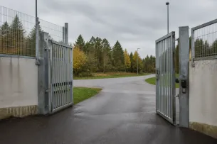 Anstaltsgrind som öppnas mot väg i dagsljus