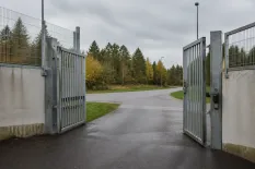 Anstaltsgrind som öppnas mot väg i dagsljus
